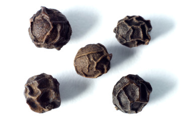 five black peppercorns of different textures