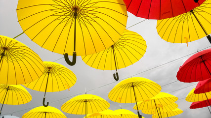 Opened yellow umbrellas hang against the sky.