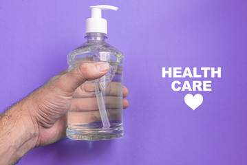 Man hand in container with alcohol gel on the light blue background