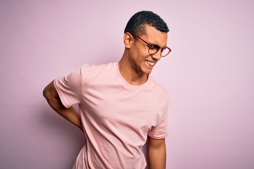 Handsome african american man wearing casual t-shirt and glasses over pink background Suffering of backache, touching back with hand, muscular pain