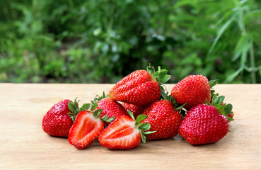 Ripe juicy strawberry ( garden strawberry, Fragaria x ananassa ) on wooden table in garden