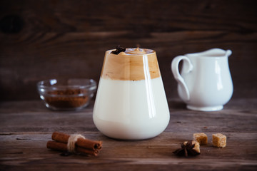 Whipped Dalgona coffee in a clear coffee mug on a wooden table.