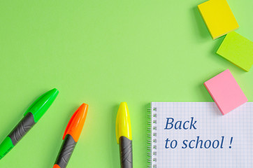 Text "Back to school" on notebook. School and office supplies on office table, green background. Flat lay, copy space.