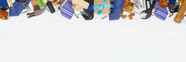Fathers Day theme long border of gifts, ties, games and tools on a white  banner background. Above view with copy space.