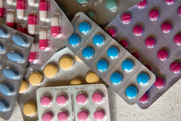 blisters of tablets of different colors - red, pink, green, blue pills and capsules
