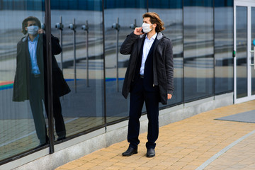 Young man in a medical mask outside, no money, crisis, poverty, hardship. Quarantine, coronavirus, isolation.