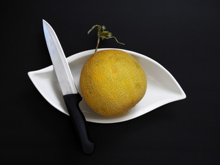 fragrant stands on a black background with a whole melon and knife,