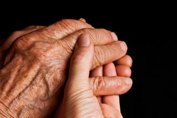 Fototapeta premium Old and young hands close-up. Aged good grandmother's hands in the hands of a young girl. Youth passes quickly. Youth and old age. Young and old hands top view. Appreciate youth she is passing soon