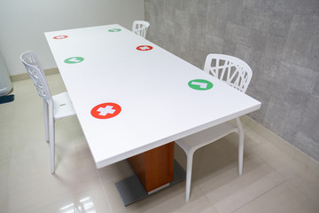 A table in a pantry of an office which only allows 3 people to have lunch which has check symbol stickers and cancel symbol stickers in pandemic for social distancing to avoid covid-19