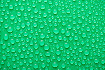 Top above overhead close up view photo of different size bright water drops on the green background