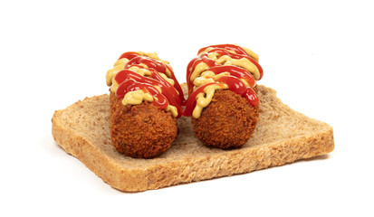 Brown crusty dutch kroket with mustard topping isolated, on a piece of bread