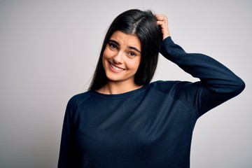 Young beautiful brunette woman wearing casual sweater standing over white background confuse and wonder about question. Uncertain with doubt, thinking with hand on head. Pensive concept.