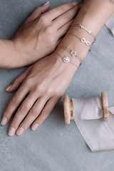 silver bracelets on a female hand on a gray background. on bracelets, decor in the form of arrows,...