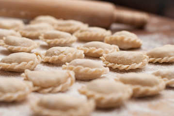 Homemade raw dumplings with filling on a wooden board