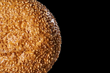 Baking. Bun with sesame seeds on a black background. Fragment. Close up.