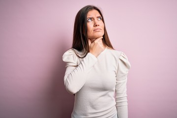 Obraz premium Young beautiful woman with blue eyes wearing casual white t-shirt over pink background Touching painful neck, sore throat for flu, clod and infection