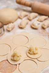 Homemade raw dumplings with filling on a wooden board