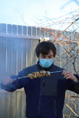 a man in a mask at the dacha roasts eats barbecue, what to do in quarantine