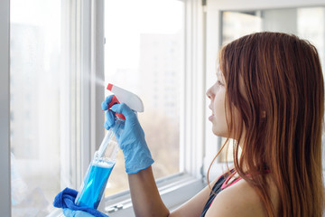washing Windows with a blue microfiber rag and a special window cleaner spray at home