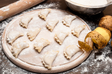 Homemade raw dumplings with filling on a wooden board