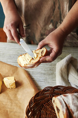 Female hands make a sandwich. Woman spreads butter on a bun