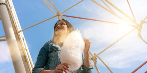 young teen girl with candy cotton in hand resting in amusement park
