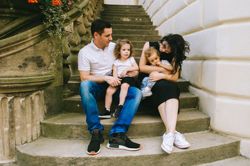 Fototapeta premium Handsome young father and beautiful mother in sunny summer nature playing with their cute small childrens