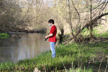 a masked man on a river fishing during quarantine, a violation of self-isolation during the coronavirus pandemic