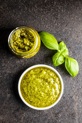 Green basil pesto dip sauce and basil leaves.