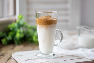 Dalgona coffee with ice and fluffy creamy whipped instant coffee on wooden tray. Trend korean drink latte on marble brown table