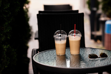 cold plastic glass of latte on glass table on cafe terrace