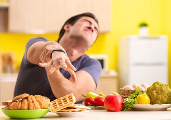 Man having hard choice between healthy and unhealthy food