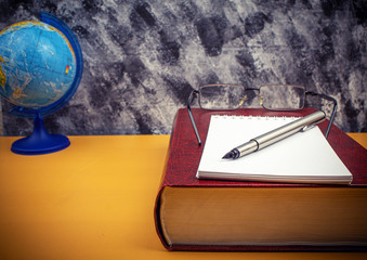 Books with glasses and a globe on the table side view