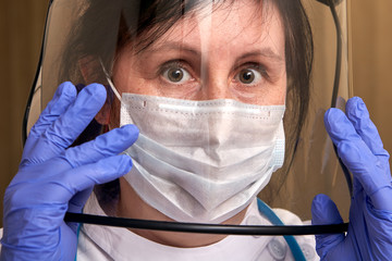 Female doctor uses a protective face shield.