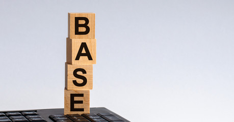 BASE-text on wooden cubes located on the keyboard, gray background.