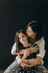 Loving mother and daughter gently hug each other, they smile and enjoy communication. A photo with a blurred background.