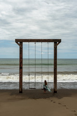 Lonely woman on a swing at a beach