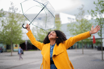 Hübsche lachende Frau mit Regenschirm in der Stadt 