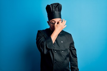 Middle age handsome grey-haired chef man wearing cooker uniform and hat tired rubbing nose and eyes feeling fatigue and headache. Stress and frustration concept.