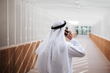 Emirati guy taking selfie in the urban city lifestyle downtown the heart of Dubai. Arabic guy wearing kandura taking site visit for expo 2020.