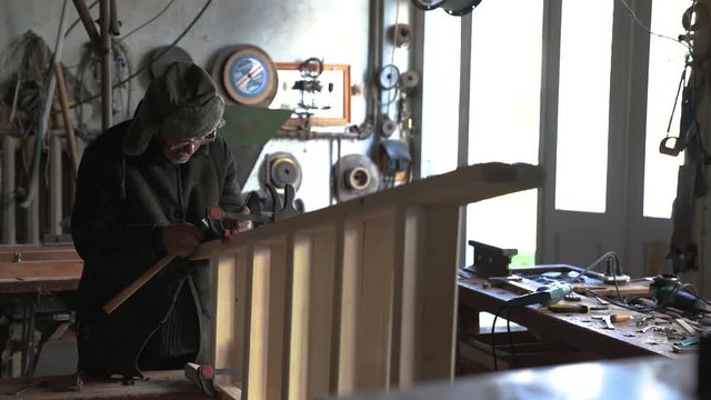 Concentrated senior carpenter making wooden stepladder in his home workshop