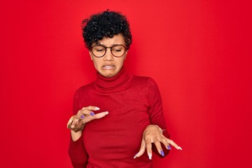 Young beautiful african american afro woman wearing turtleneck sweater and glasses disgusted...