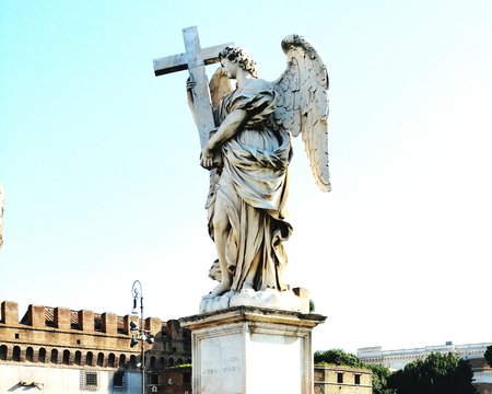 Low Angle View Of Angel Carrying Cross Statue Against Sky