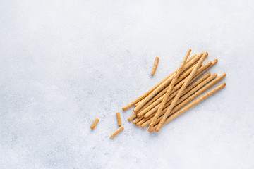 Organic Italian grissini or salted bread sticks and bread lying on a gray background. Fresh Italian snack for apero. Top view, copy space