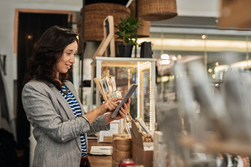 Smiling young Asian woman using a tablet in her store
