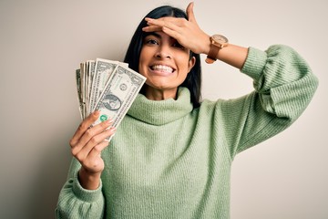 Young beautiful hispanic woman holding a pack of one dollar bunch of dollars stressed with hand on head, shocked with shame and surprise face, angry and frustrated. Fear and upset for mistake.