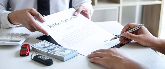 Realtor agent manager holding rental contract form to woman client for decide signing to agreement, renting considering vehicle car insurance