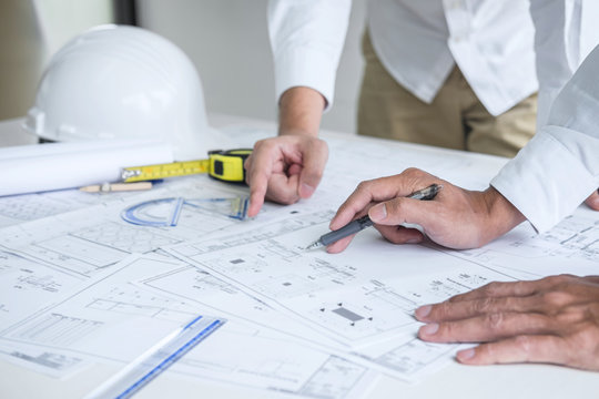 Team of engineering or architect meeting and discussing on blueprint and building model while checking information on sketching for architectural project
