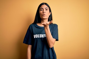 Young beautiful hispanic woman wearing volunteer t-shirt as social charity moral looking at the...