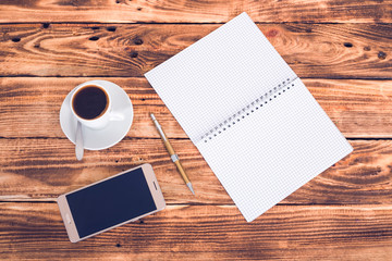 cup coffee copybook and phone in wooden background